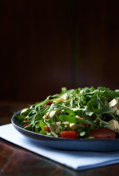 Green salad with feta cheese, olives and arugula leaves. Rustic wooden background. Soft focus.