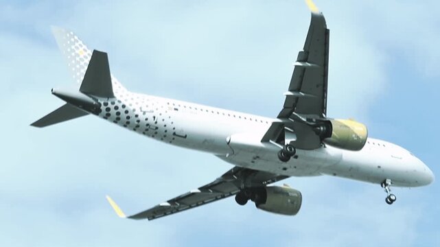 Close-up of a passenger jet in flight through, viewed from below, from the side with motion blur. Commercial flights through a travel agency. Flight reductions, cancellations, energy crisis, tourist