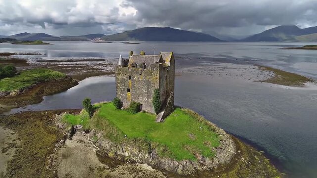 Cinematic drone footage slowly flying through low clouds and mist over the rugged mountains of the Scottish Highlands. The aerial camera glides smoothly through the atmospheric landscape,