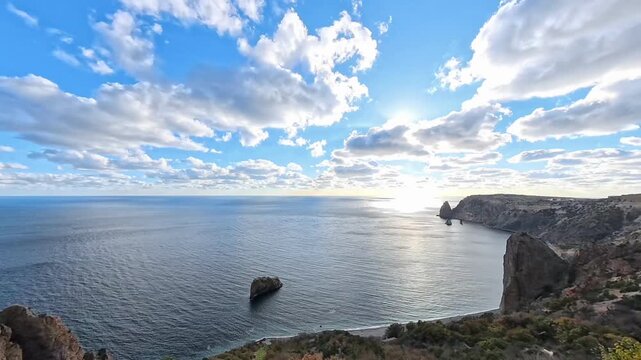 Coastal cliffs ocean panoramic view of high rocky slopes meeting calm sea under bright sunny sky and scattered clouds