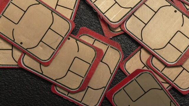 A collection of SIM cards with distinctive red edges scattered on a textured black surface. Ideal for technology or telecommunications themes.