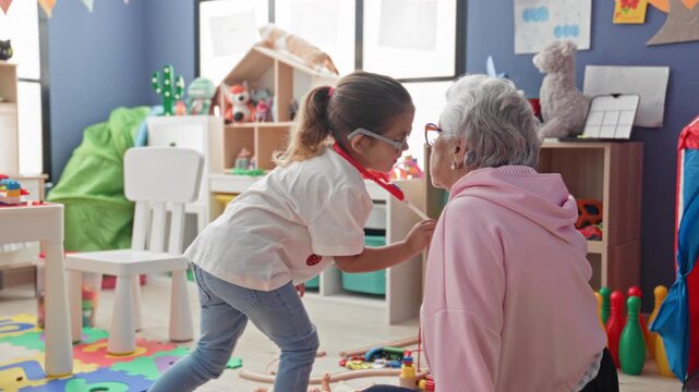 Girl kneels and uses red stethoscope on seated senior woman amid colorful toys and shelving in a children's playroom; care.