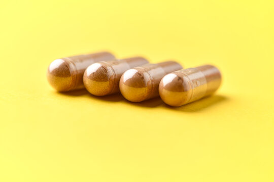 Ashwagandha (Withania somnifera) capsules. Concept for a healthy dietary supplementation. Bright paper background. Soft focus. Close up. Copy space.
