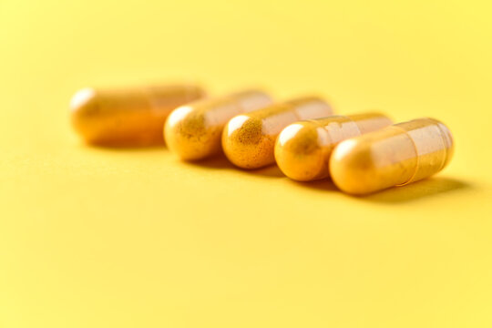 Turmeric capsules. Bright paper background. Soft focus. Close up. Copy space.