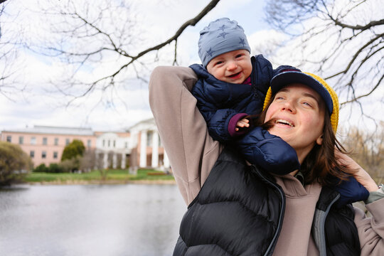 Happy mother carrying baby on shoulders by the lake