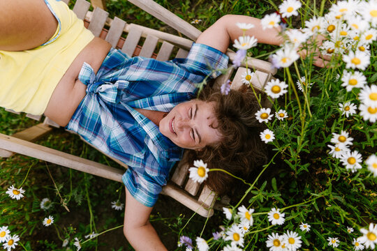 Relaxing on a deck chair in a summer garden full of daisies