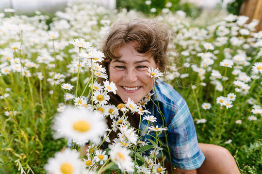 Smiling gardener in a summer garden with blooming daisy flower