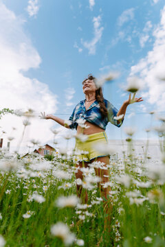 Smiling woman standing in a daisy meadow enjoying freedom