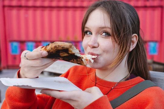 Customer eating a slice of cheese pizza outdoors