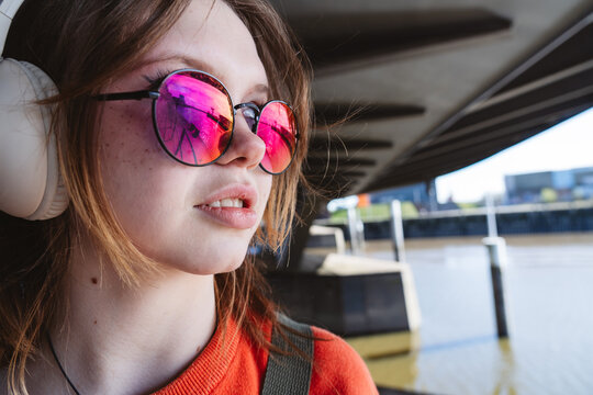 Girl outdoors with headphone and pink eyewear listening to music