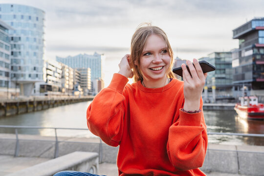 Smiling tourist recording voice message outdoors at HafenCity