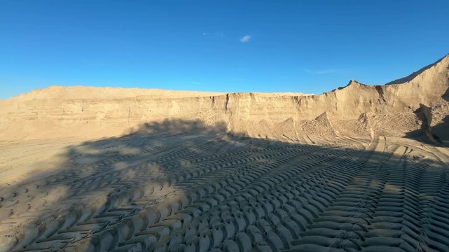 Large sand quarry with tire tracks under blue sky