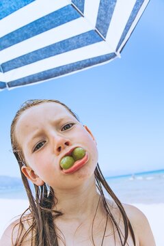 Child making funny face with olive in mouth at the beach