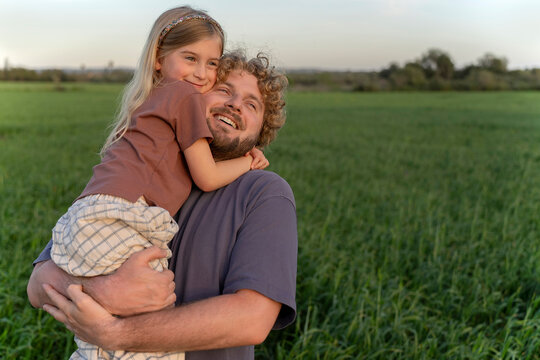 Happy father and daughter hugging in a green field