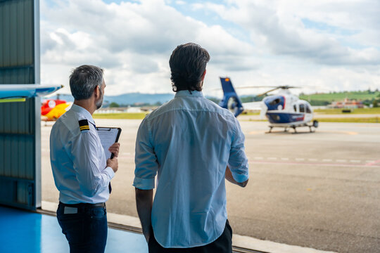 Pilots discussing flight plan near airplane hangar