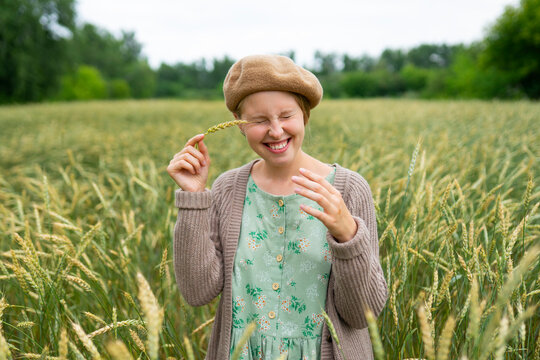 Young woman enjoying summer in a wheat field wearing a vintage dress
