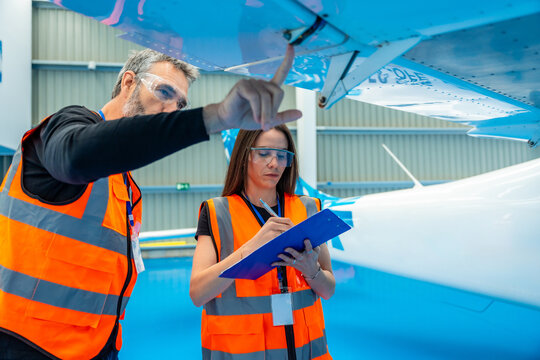 Aviation technicians performing aircraft inspection checklist in hangar