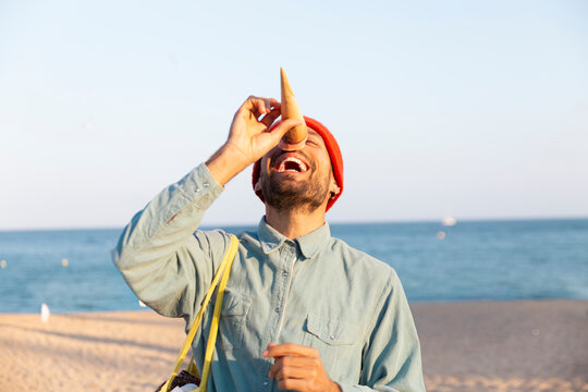 Happy tourist laughing with ice cream cone on Barcelona beach