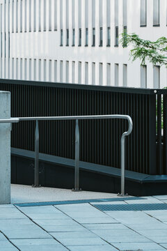 White facade, black wall and railing define modern architecture in an urban exterior, where shadow and a small tree add clean geometric detail