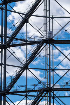 Steel framework and stair structure cross the blue sky, turning industrial architecture into an urban abstract detail of lines, shadow and geometry