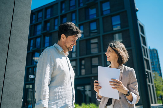 Smiling colleagues discussing real estate mortgage outdoors