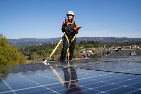 Technician communicating via walkie talkie on solar panel rooftop