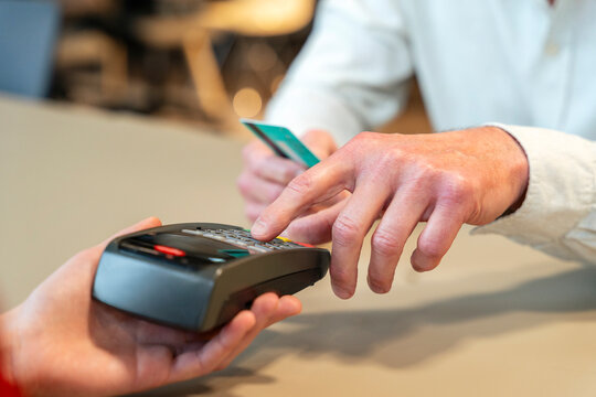 Customer entering pin code on payment terminal at retail counter