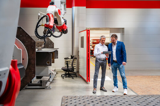 Manager and engineer discussing production on tablet in factory