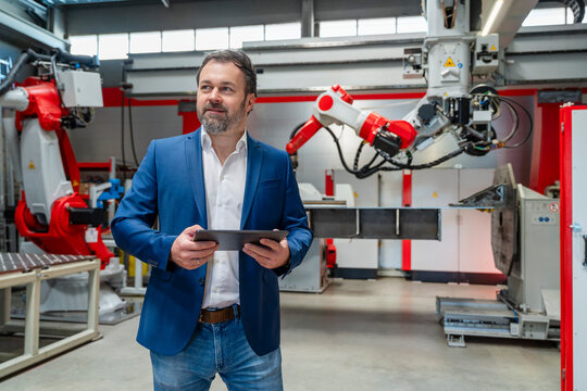 Manager holding tablet in modern automated manufacturing plant