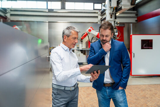 Employees planning production with tablet in automated factory