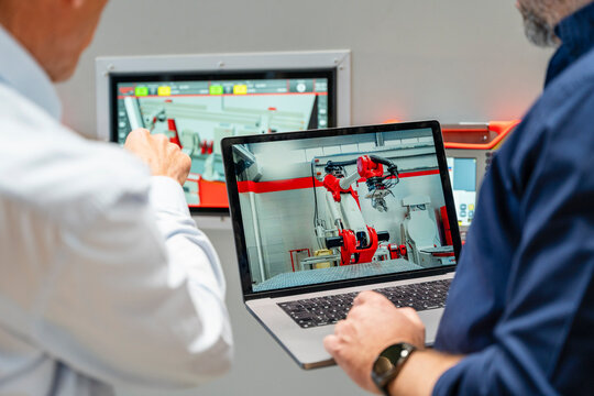 Team planning industrial robot automation on laptop screen