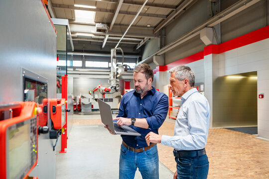 Employees planning with laptop in modern manufacturing factory