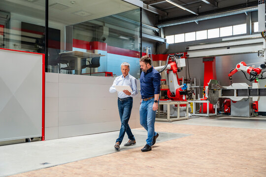 Manager and engineer walking with tablet in automated factory