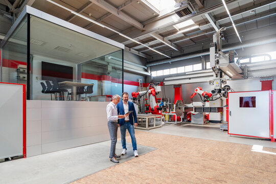Engineers planning with tablet in modern production hall