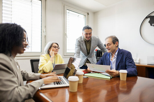 Supervisors and employees working with laptops in an office meeting