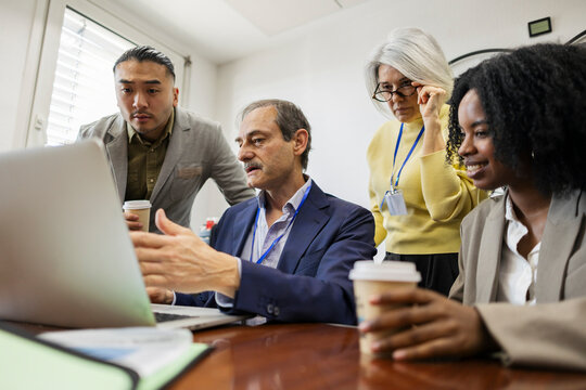 Coworker pointing at laptop during manufacturing office meeting