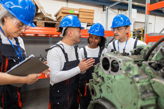 Engineering team discussing engine in industrial warehouse