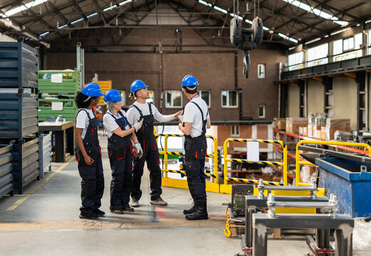 Team of engineers discussing production in industrial warehouse