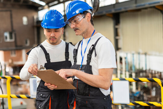 Supervisor checking clipboard during maintenance shift at factory