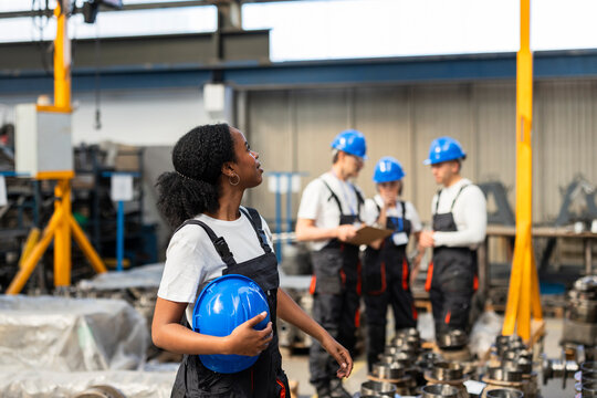 Supervisor carrying hard hat walking in manufacturing factory