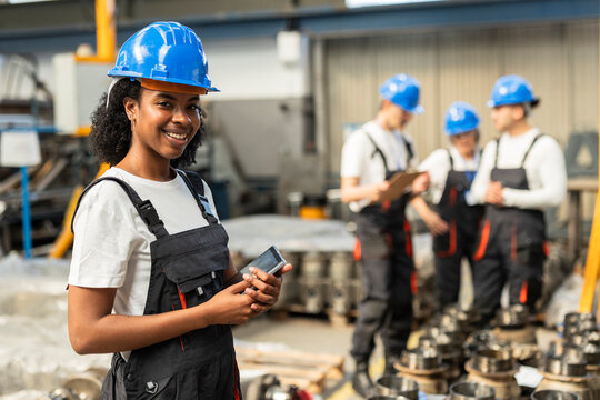 Smiling factory supervisor with smartphone standing indoors