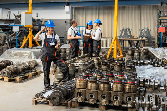 Supervisor looking at camera with coworkers in factory