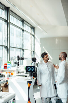 Scientists talking next to a robot in a modern laboratory
