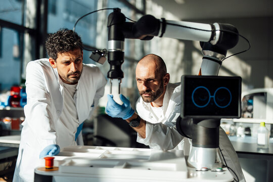 Researchers examining robotic arm in modern laboratory