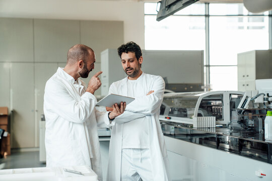 Scientists discussing research on digital tablet in laboratory