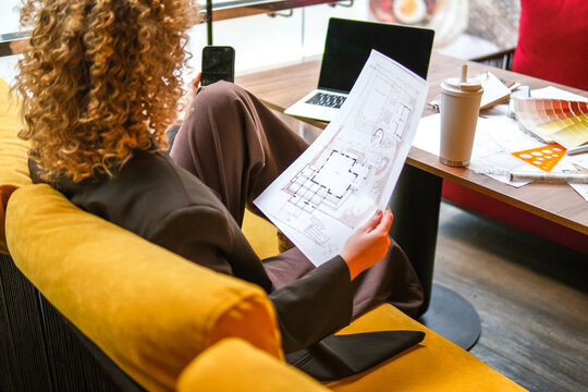 Architect holding blueprint and smartphone working indoors