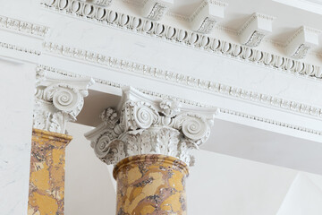 Fototapeta premium Ornate Corinthian column with carved acanthus capital and yellow marble shaft set against white classical molding, ceiling details, evoking historic architecture, elegance and interior craftsmanship