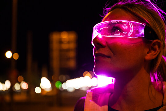 Portrait of woman with pink augmented reality visor in city at night