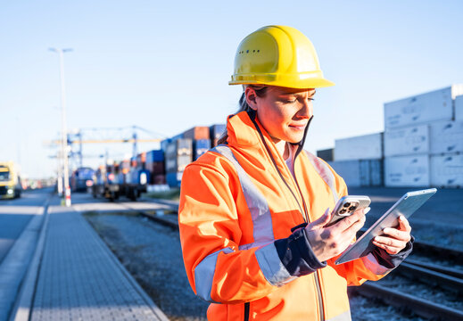 Logistic worker holding tablet and smartphone at cargo terminal