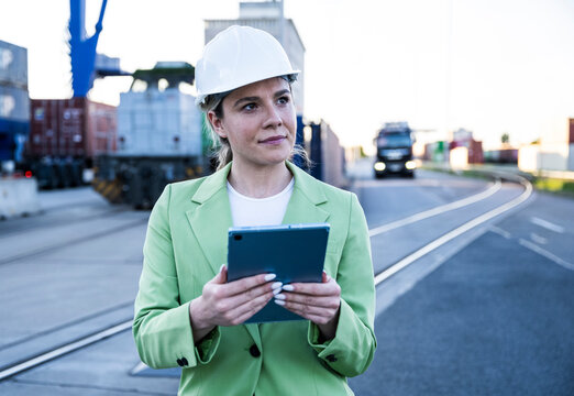 Businesswoman in hardhat working with tablet at logistics port